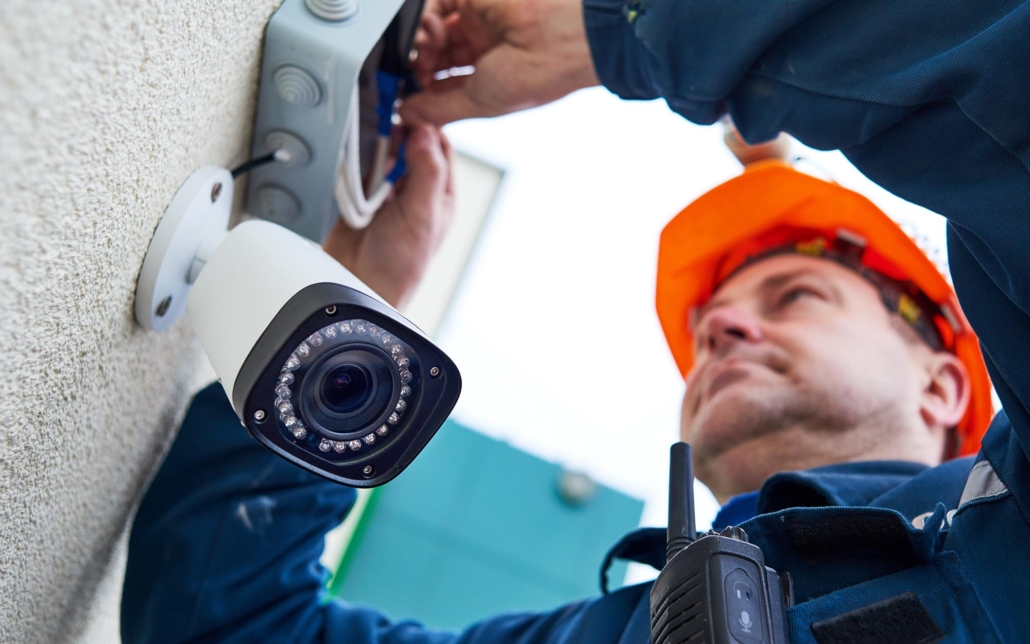 A professional from Verkada Security works on fixing a camera, carefully adjusting and troubleshooting the device. Their focused expression and precise actions emphasize their expertise in maintaining and ensuring the functionality of security equipment.