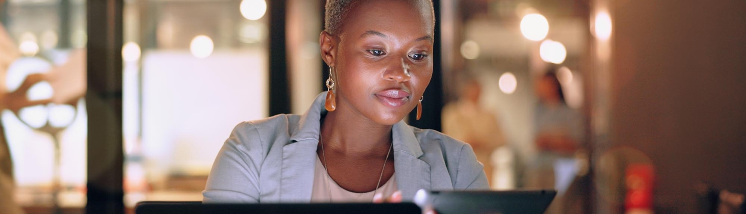 Front view of a woman working on a computer and smart tablet