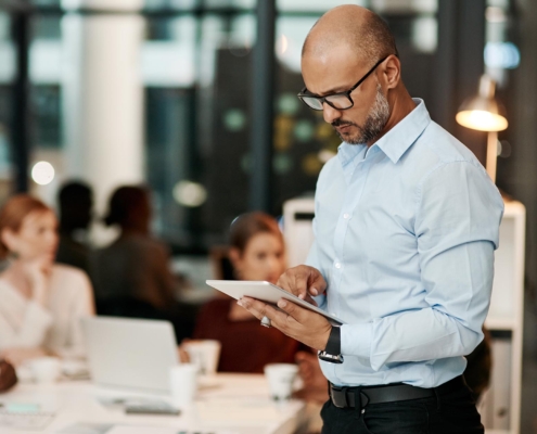 A man views a smart tablet from the side, intently interacting with the screen. His focused posture and engaged expression suggest he’s actively using the device for work or personal tasks.