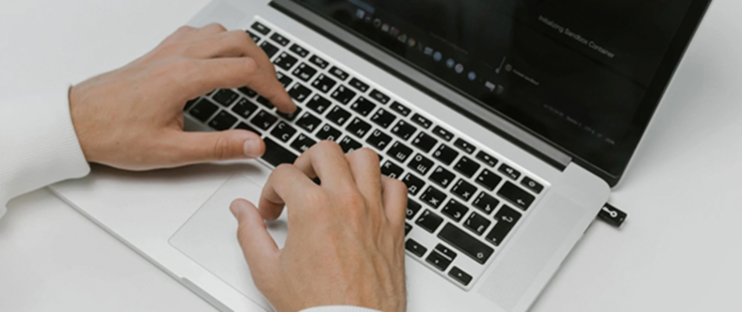 A businessman’s hands rest on a laptop keyboard, engaged in typing or reviewing information. The focused posture suggests active involvement in work tasks, reflecting a blend of professionalism and productivity.