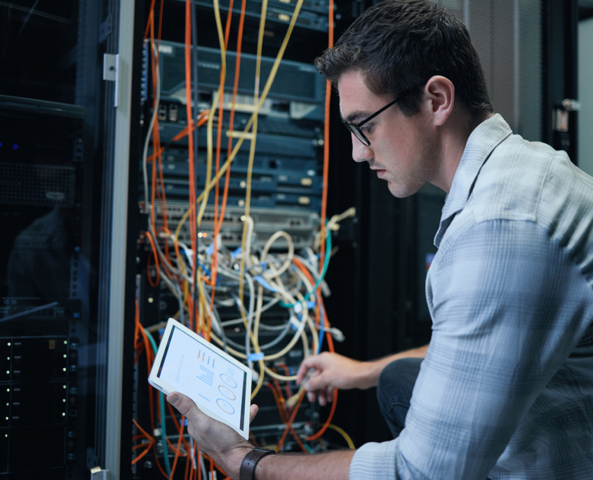 Side view of a man working on a tablet in a server room